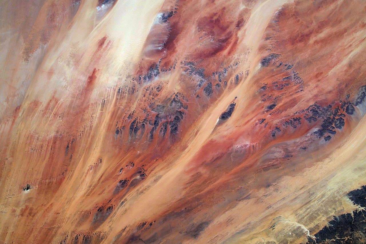 Saharan dunes today. Satellite radar reveals buried river systems beneath the sand — the Tamanrasset Paleoriver was longer than the modern Rhine.